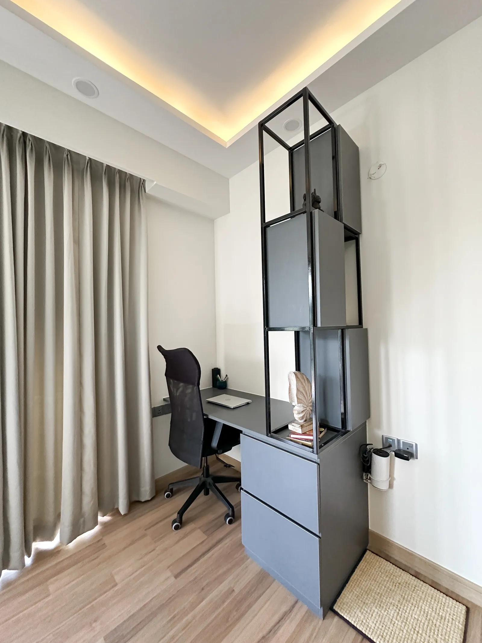 Study corner with grey desk and open shelving unit — Somani's Residence